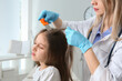 © New Africa - Doctor using nit comb on girl's hair in clinic. Anti lice treatment