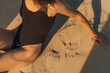 © Olga Moreira/Stocksy - Woman at the beach sitting on the sand
