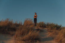 Woman In Black Clothes Standing On Top Of The Dune