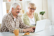© chagin - Elderly couple talking using laptop having breakfast together