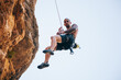 © ADDICTIVE STOCK - Adventurer man wearing safety harness climbing mountain