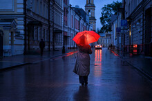 A Woman With A Red Umbrella Outside A Dark City Street