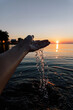 © Kelly Knox/Stocksy - woman pouring water from her hand over a lake at sunset