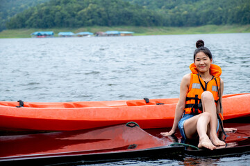 Asian girl in orange life jackets with the backdrop of water and mountains Ready for travel as a hobby