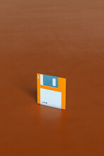 One Single Blue And Orange Floppy Disks On Brown Background