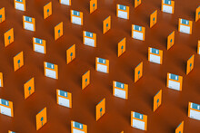 Pattern Of Blue And Orange Floppy Disks On Brown Background