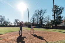 Young Cinematographer Filming A Woman Up To Bat On Baseball Field