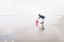 Boy Fills Bucket With Sand On Beach