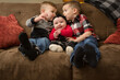 © Jennifer Bogle/Stocksy - brothers snuggle baby sister on couch