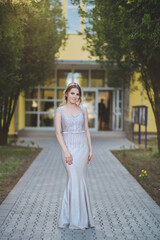 Wall Mural - Hot blonde Caucasian woman wearing a silver dress in front of a building