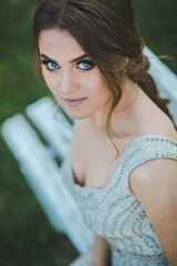 Wall Mural - Young woman with evening makeup sitting on the bench