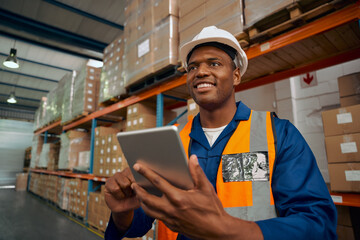 Wall Mural - Smiling factory worker inspecting the manufacture goods using digital tablet in warehouse