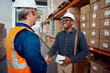 © StratfordProductions - African worker shaking hand with his partner wearing safety helmet holding tablet in hand