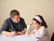© Miquel Llonch/Stocksy - Little girl studying with father at home