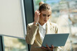 © LIGHTFIELD STUDIOS - thoughtful businesswoman fixing hair while looking at laptop in office