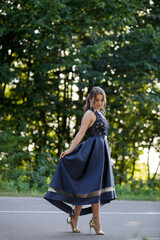 Poster - Vertical shot of an elegant caucasian female in a blue evening dress standing on a road