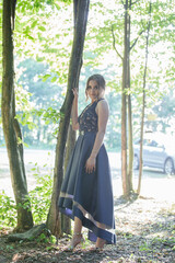 Poster - Sexy Caucasian woman with a dark blue dress and heavy makeup posing in the park