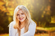 Portrait Of Attractive Smiling Blonde Posing In Autumn Park On Sunny Day