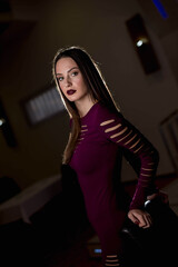 Poster - Attractive Caucasian female wearing a burgundy dress posing in a dark room