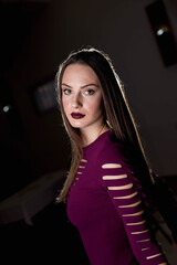 Poster - Sexy Caucasian woman with a dark purple dress and heavy makeup posing in a dark room