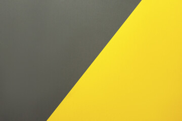 Background of two colors. Yellow and gray colored paper sheets divided diagonally. Flat lay, top view.