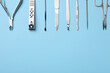Set of manicure tools on light blue background, flat lay. Space for text