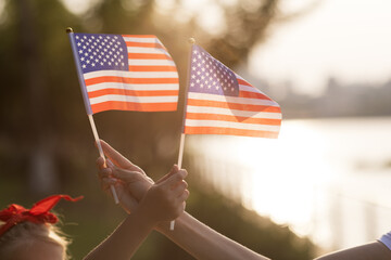 Patriotic holiday. Happy family, mother and daughter with American flag outdoors on sunset. USA celebrate independence day 4th of July.