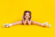 Full length body size photo schoolgirl wearing rollers doing stretching exercises isolated bright yellow color background
