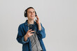 © Drobot Dean - Young brunette man with headphones smiling and holding cellphone