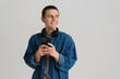 © Drobot Dean - Young brunette man with headphones smiling and holding cellphone