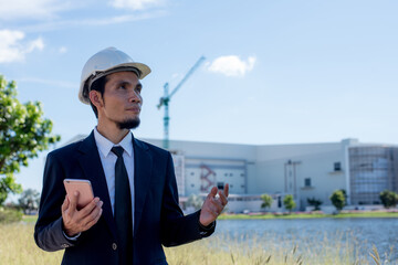 businessman with a cellphone in hand and standing at a building construction site.