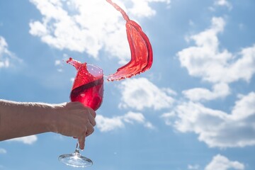 Wall Mural - splash of red wine in a glass against the blue sky, close-up, beautiful.