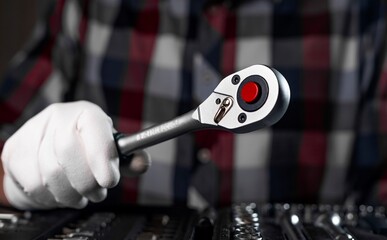 Wall Mural - Metal tool, socket ratchet handle, in male hand of repairman in checkered shirt, close up.