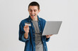 © Drobot Dean - Young man smiling while holding credit card and laptop