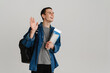 © Drobot Dean - Young student man smiling and waving while holding exercise books