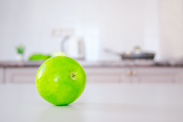 green apple on the white kitchen table. cozy kitchen. free space for text