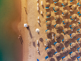 Wall Mural - Aerial view of sandy beach with colorful umbrellas, swimming people in sea bay with transparent blue water at sunset in summer. Travel in Egypt. Top view.