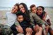 © Erin Brant/Stocksy - Happy Black family cuddled together at beach