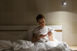 © Danil Nevsky/Stocksy - Young woman applying hand cream sitting in bed