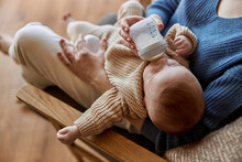 Mother Feeding Newborn Baby From Bottle With Milk
