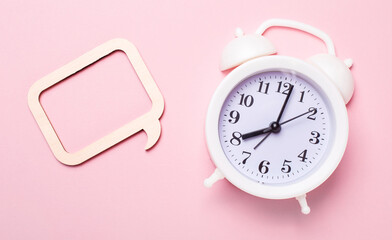 On a delicate pink background, a white alarm clock and a frame with a place to insert text or an illustration. Template