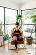 © Kristen Curette & Daemaine Hines/Stocksy - A woman drinking tea in workout clothes, sitting by the window.