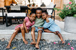 © Kristen Curette & Daemaine Hines/Stocksy - Three kids playing outside in the backyard sitting on the patio.