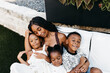 © Kristen Curette & Daemaine Hines/Stocksy - An African American mother with her children sitting on her lap.