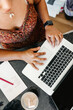 © Kristen Curette & Daemaine Hines/Stocksy - A birds eye view of a woman working on a laptop with a notepad & iced coffee.