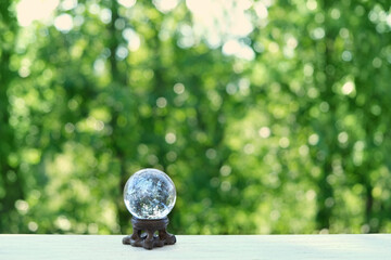 Wall Mural - magic clear quartz ball on green natural background. beautiful crystal ball for meditation, relaxation, Witchcraft. healing gemstone. spiritual practice