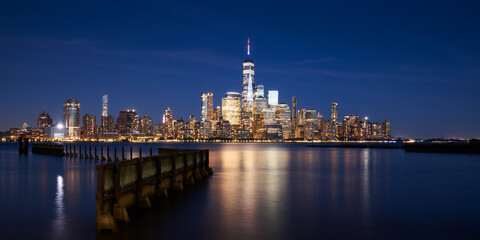 Fototapete - The skyscrapers of the Financial District in Lower Manhattan of New York city at Dusk. Reflection upon Hudson River of World Trade Center buildings, NYC, USA