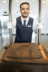 Sticker - Young porter in uniform pushing cart with suitcases