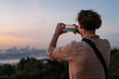 © Alina Hvostikova/Stocksy - Unrecognizable traveler taking photo of city at sunset