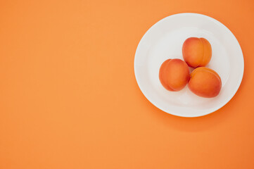 Canvas Print - Top view of fresh three apricots on a plate isolated on orange background